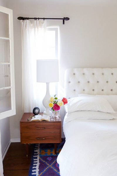 White tufted headboard with white bedding but bight rug.